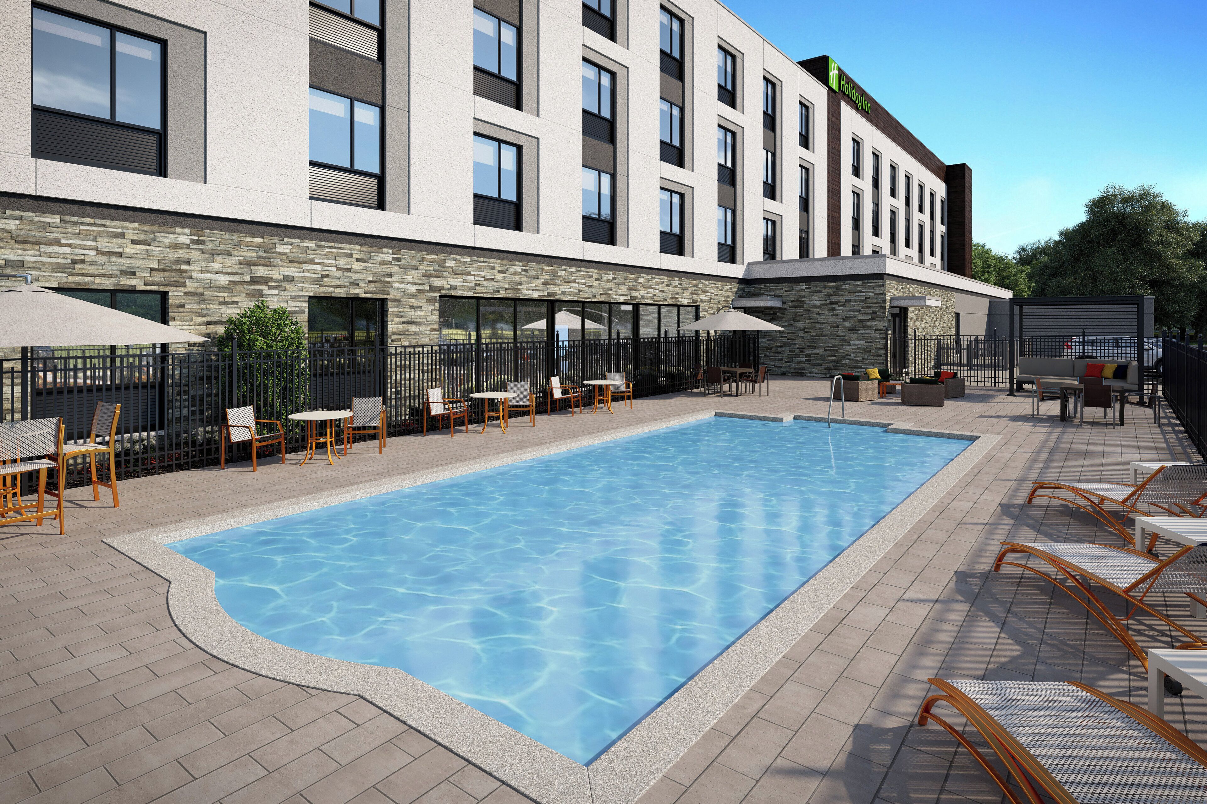 A modern hotel with a swimming pool, outdoor seating, and a stone facade.