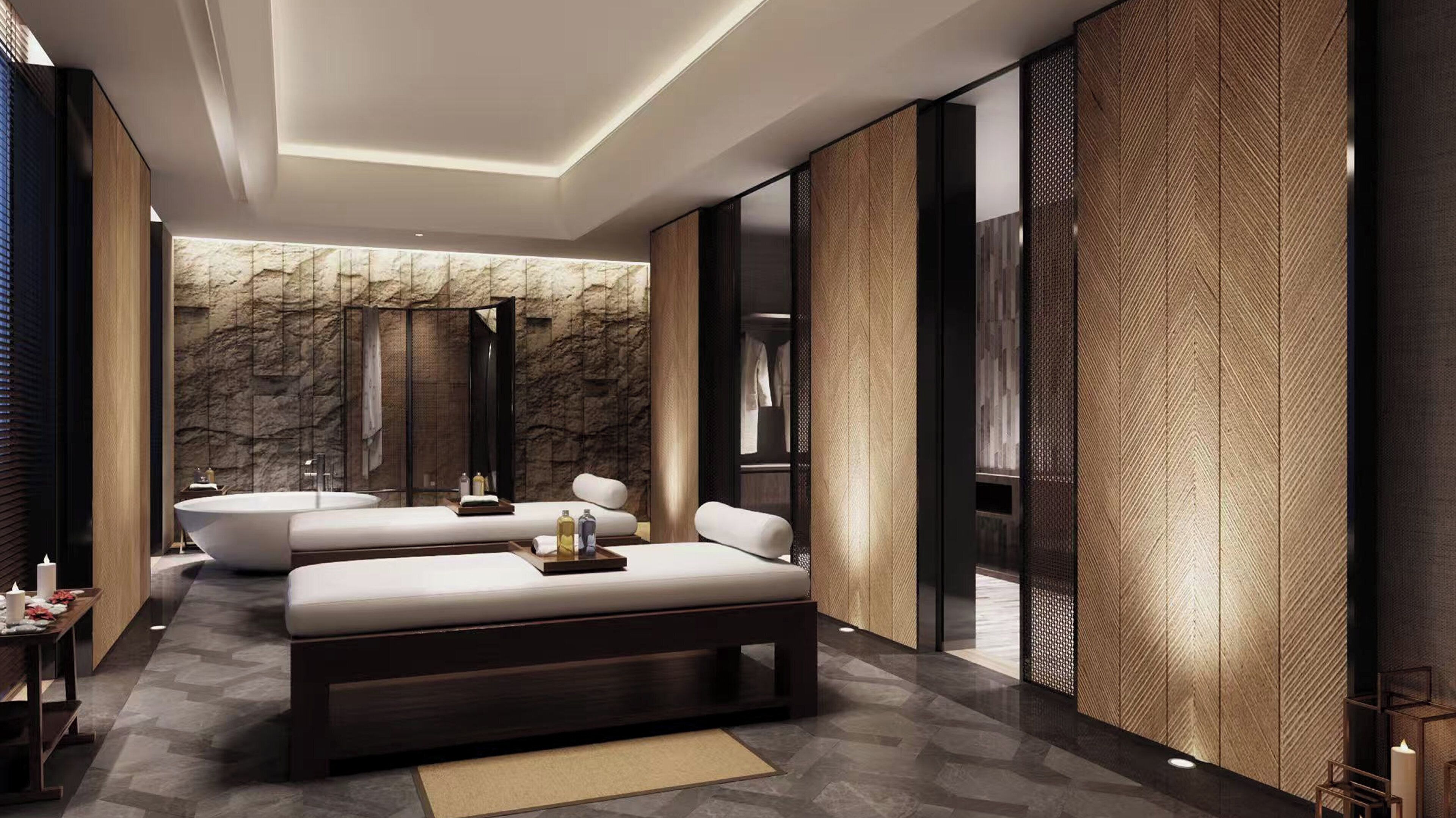 Une chambre d’hôtel moderne dotée d’un grand lit, d’un coin salon séparé, d’une baignoire et d’un mur décoratif en pierre.