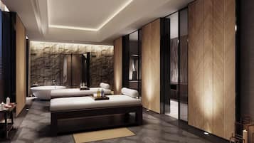 Une chambre d’hôtel moderne dotée d’un grand lit, d’un coin salon séparé, d’une baignoire et d’un mur décoratif en pierre.