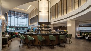 A spacious bar area with a central circular bar, multiple seating options, and a large window providing a view of the outdoors. - InterContinental Zhengzhou Zhengdong by IHG (Zhengzhou)