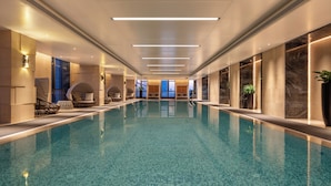 A long indoor swimming pool with a tiled floor, surrounded by walls with large windows and modern lighting fixtures. - InterContinental Zhengzhou Zhengdong by IHG (Zhengzhou)