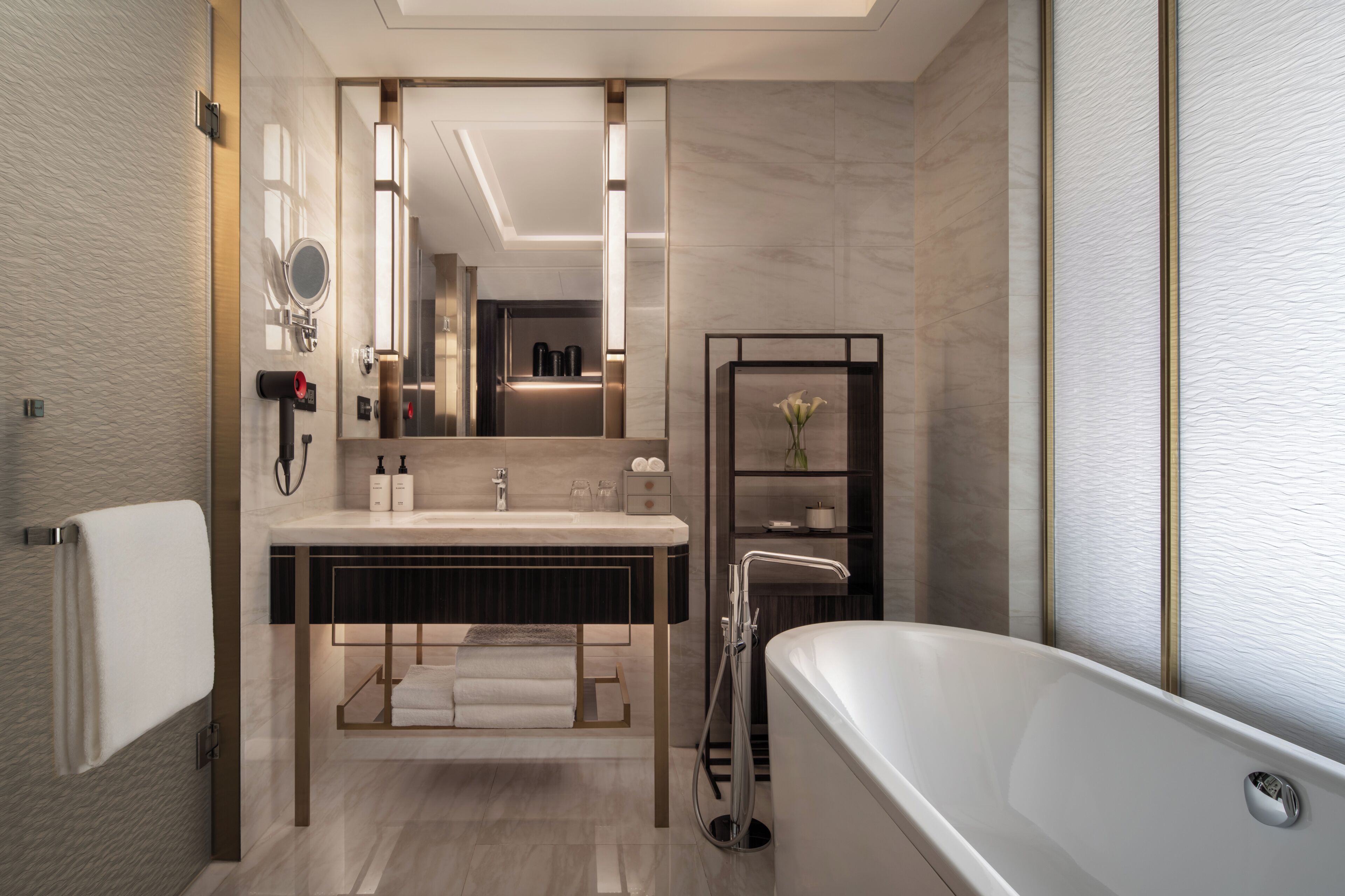 A modern bathroom with a freestanding bathtub, a vanity with a mirror, and a shelf with toiletries.