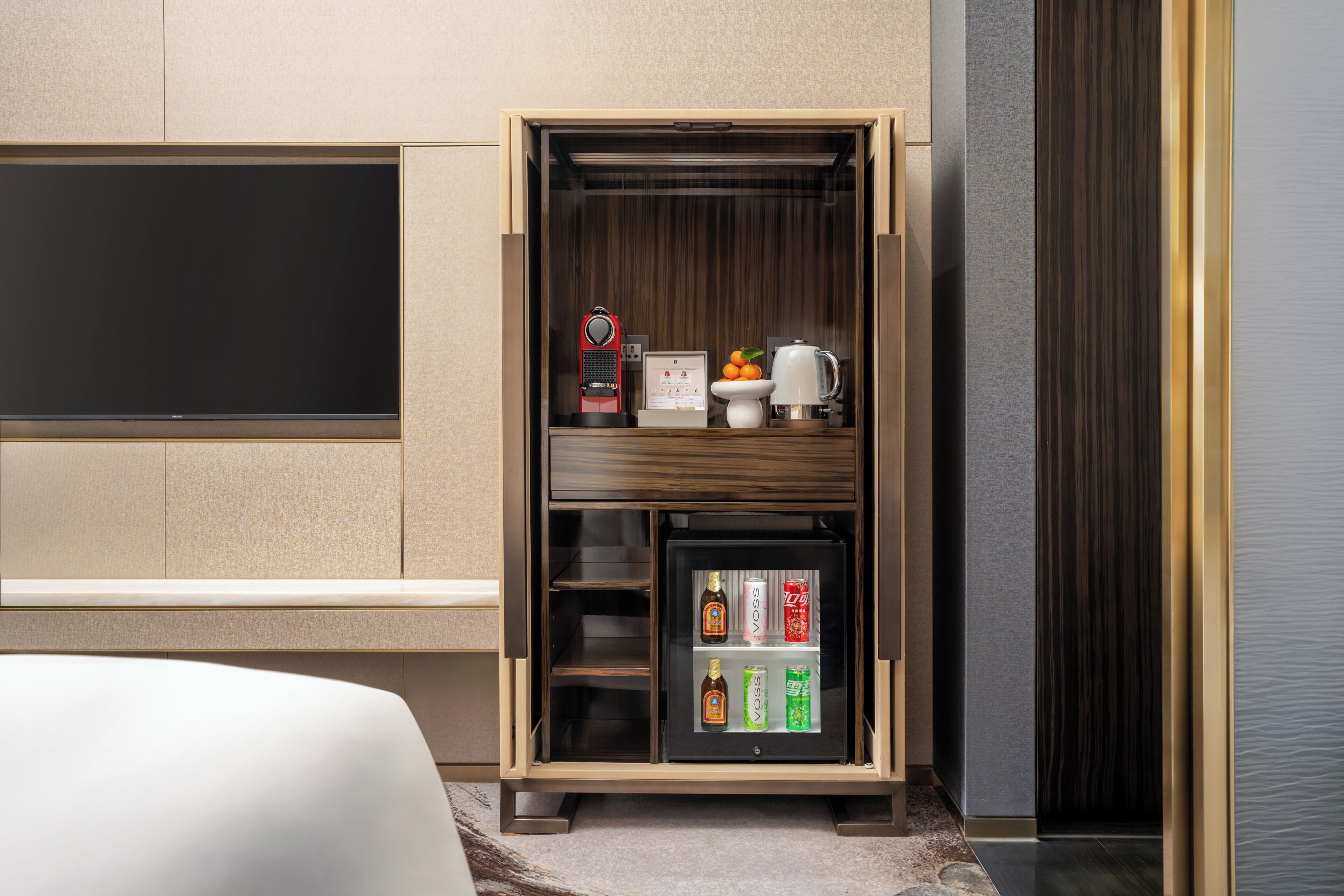 Eine Minibar mit Fernseher, einer Kaffeemaschine und einer Auswahl an Getränken.