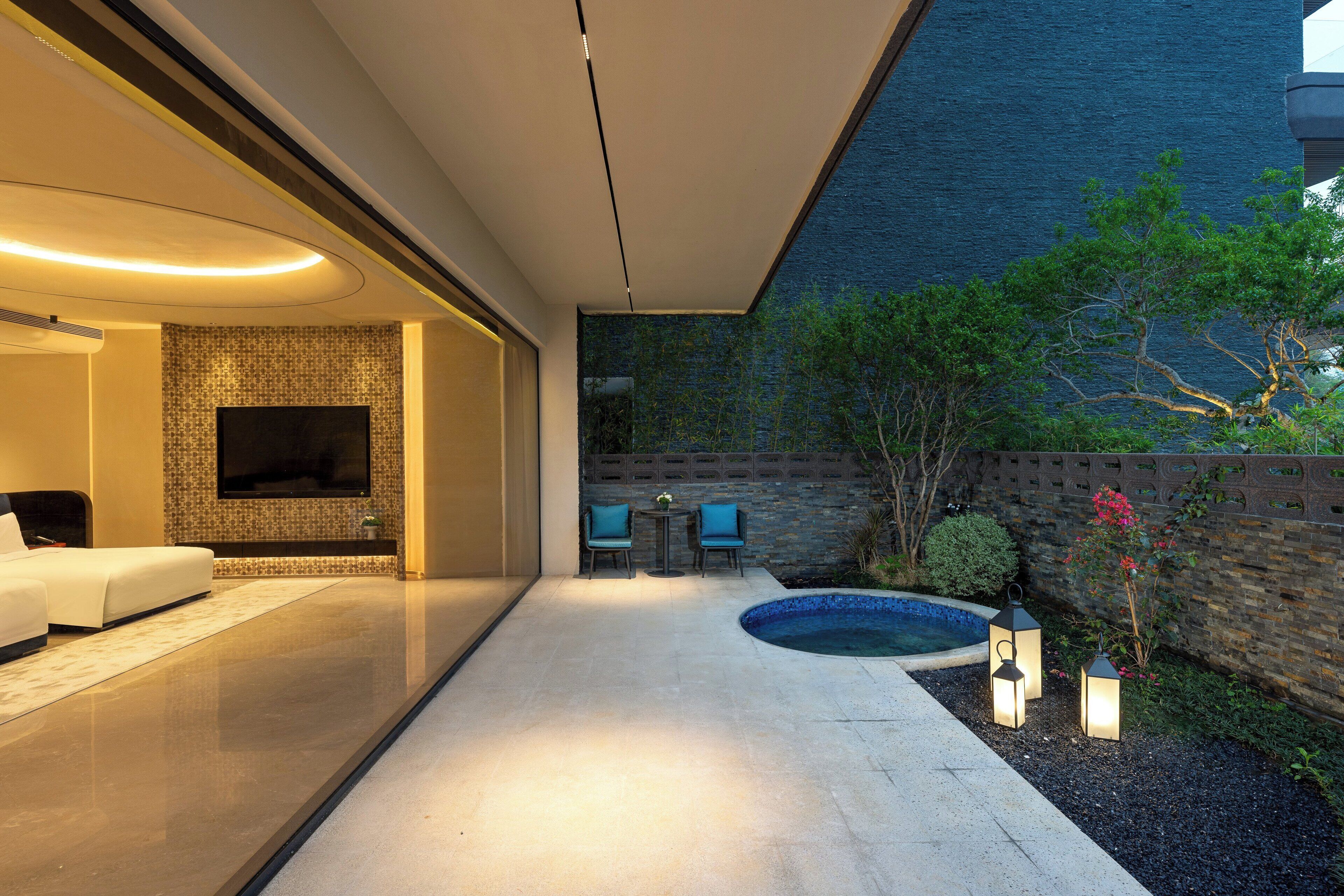 A modern outdoor living area with a flat-screen TV, seating, and a swimming pool.