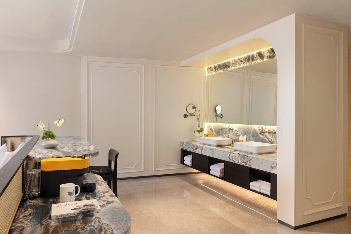 A modern bathroom with a marble countertop, dual sinks, and a large mirror.