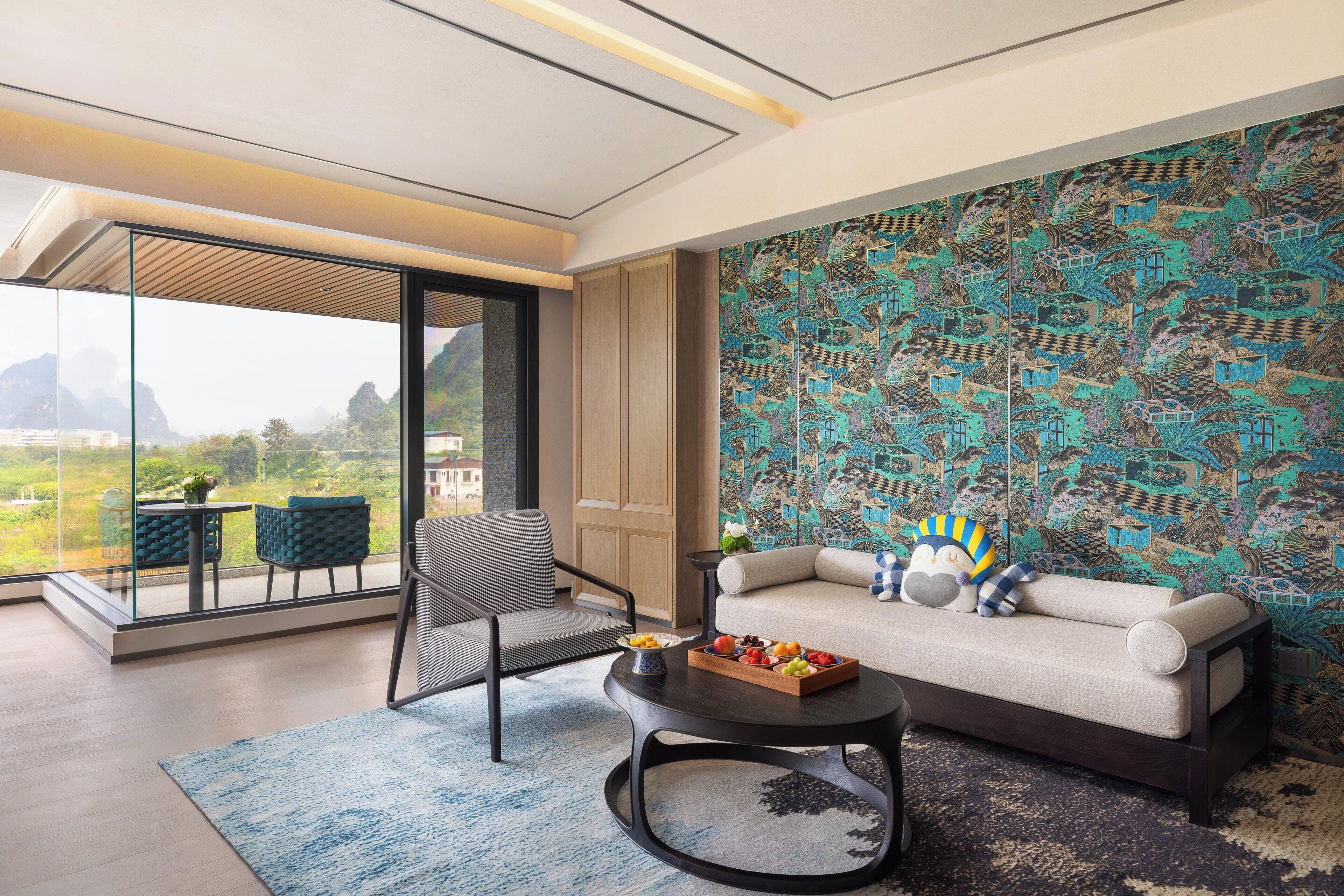 A modern living room with a sofa, a round coffee table, and a chair. There is a large window offering a view of the outdoors.