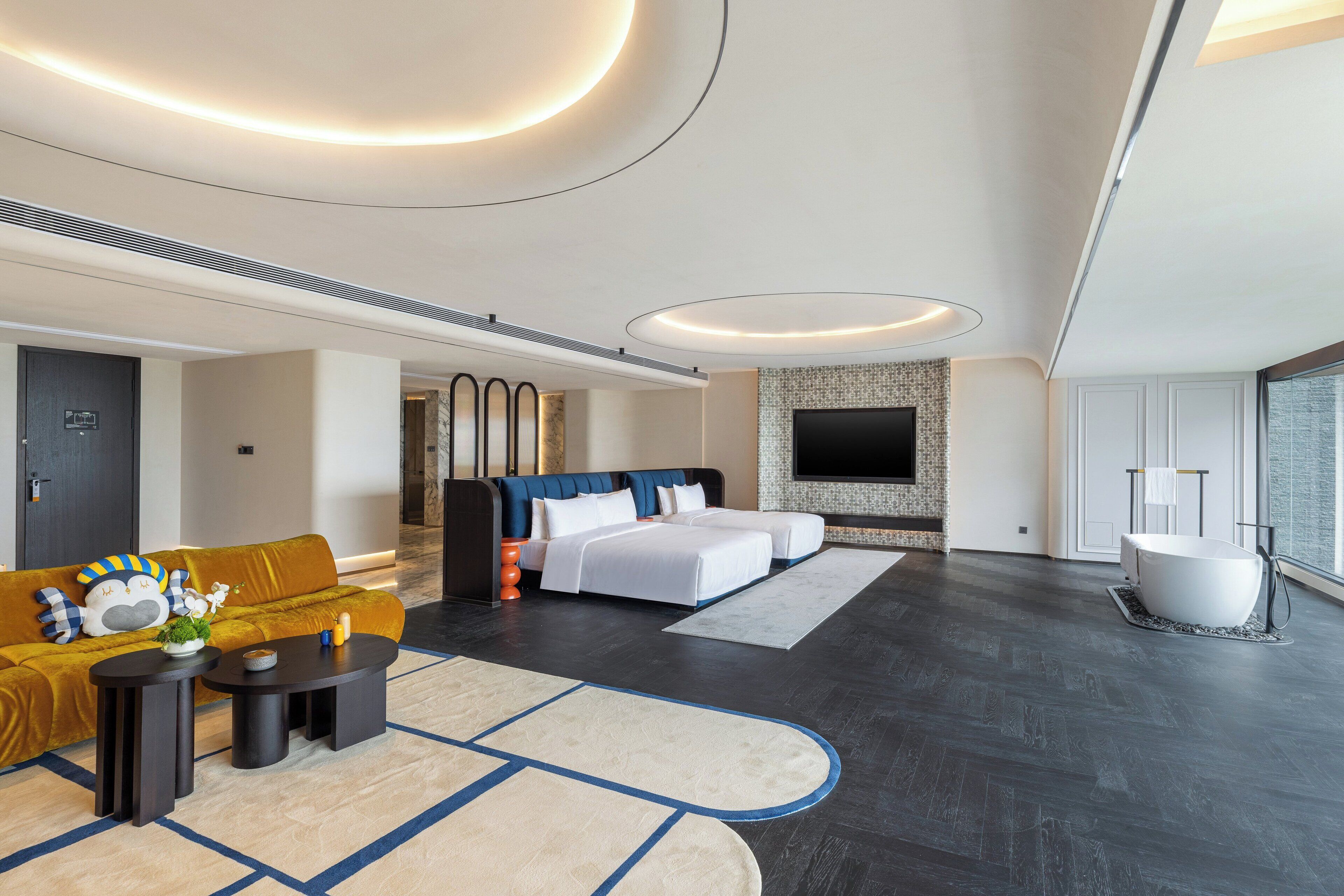 Quarto de hotel moderno com cama grande, sofá, televisão de tela plana e banheira.