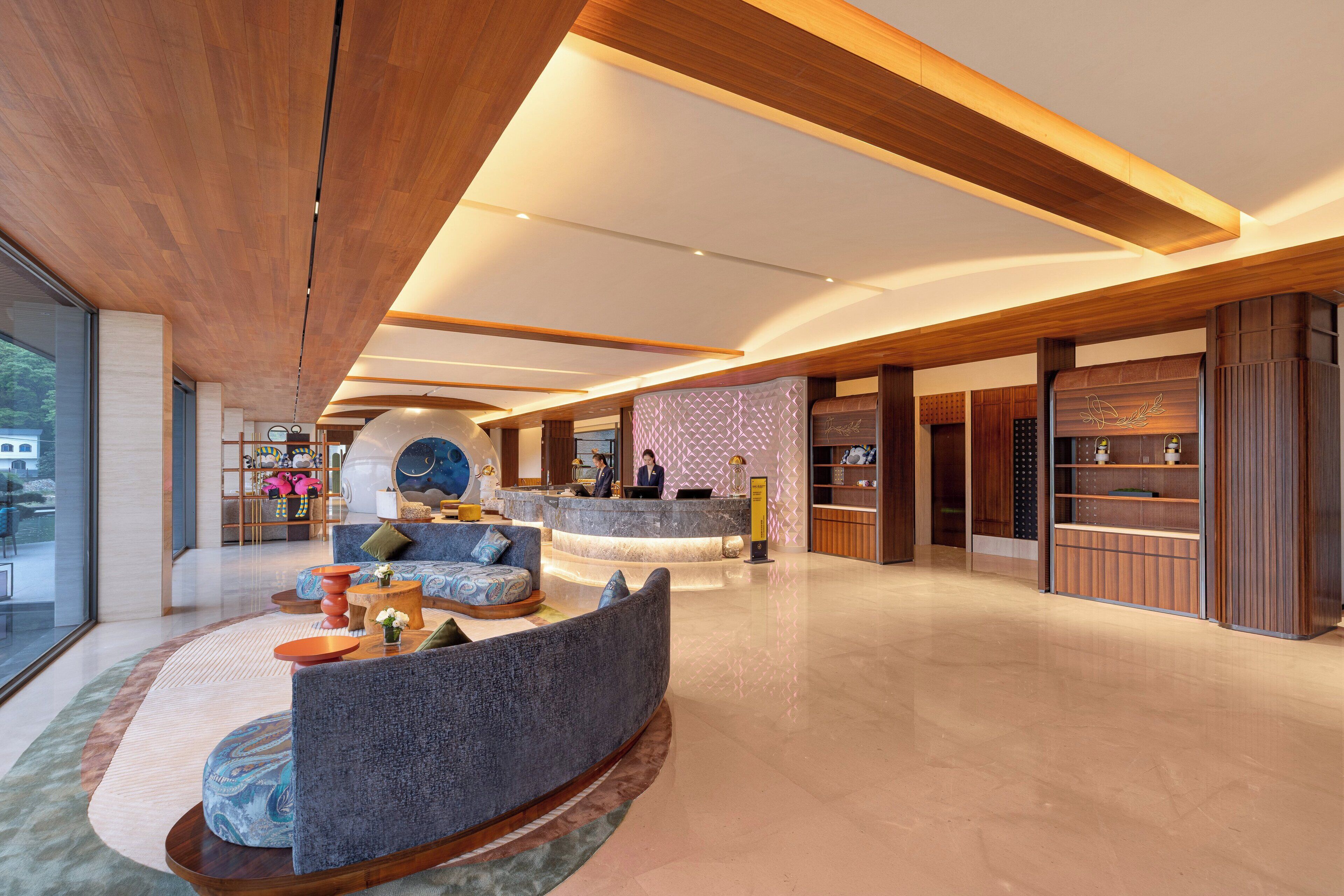 A spacious lobby with a reception desk, seating area, and wooden accents.