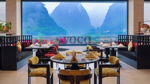 A restaurant with a large window offering a view of mountains and greenery. - voco Guilin Yangshuo by IHG (Guilin)