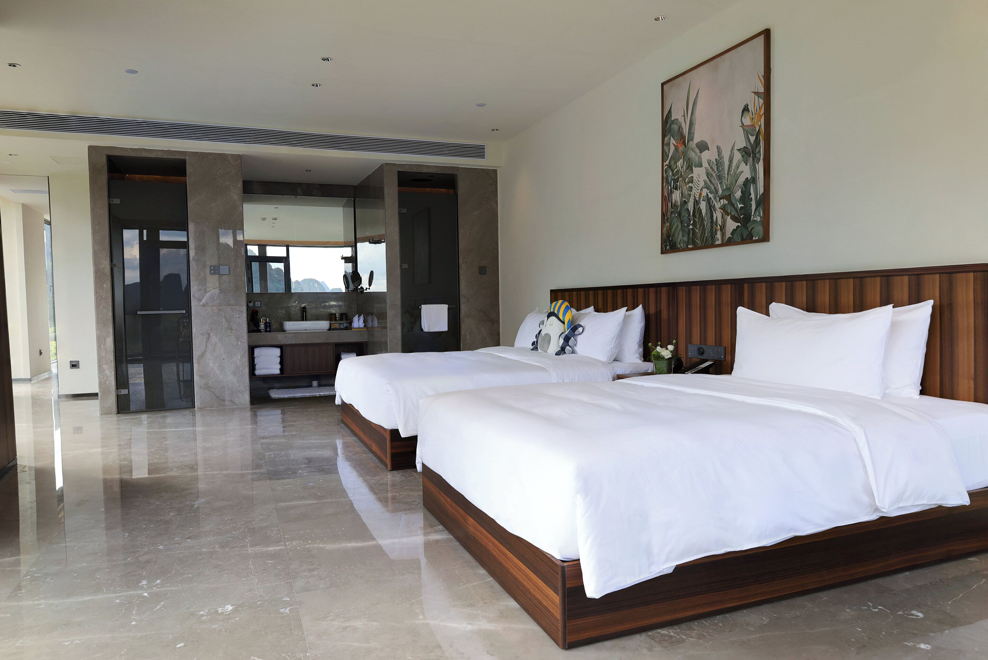 Habitación de hotel con dos camas, un baño con un espejo grande y vista a las montañas.