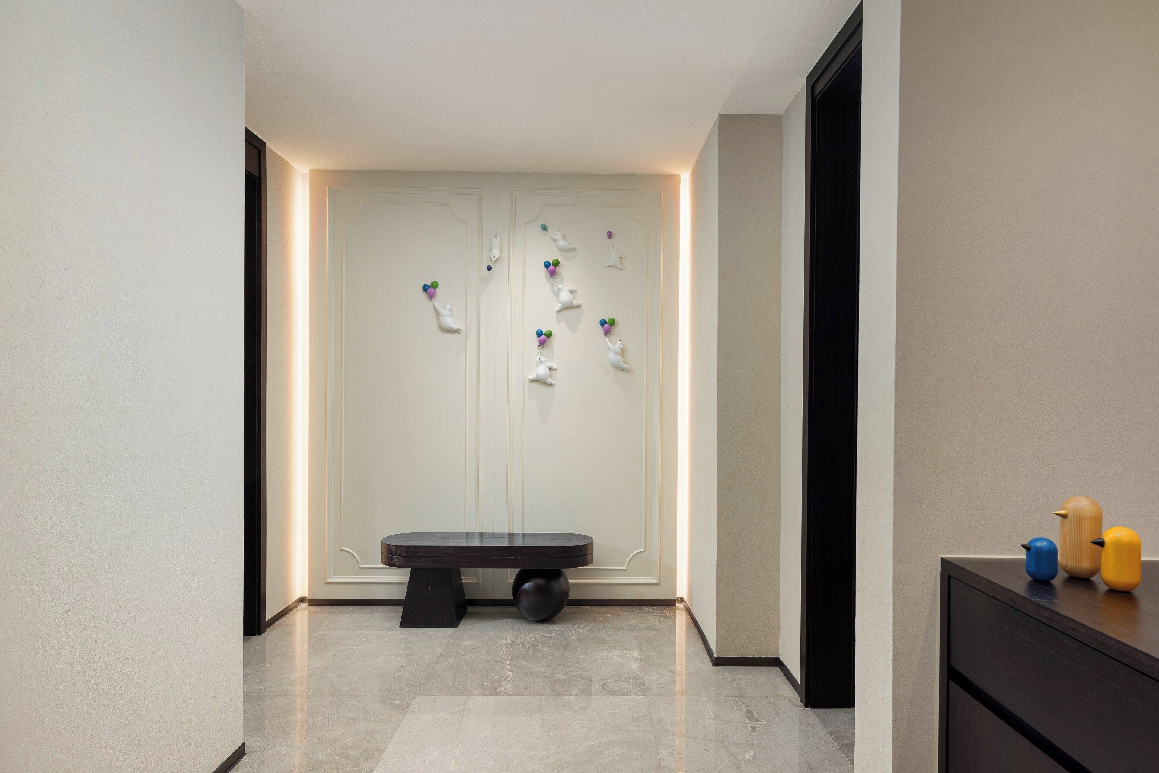 A modern hallway with a bench, a wall-mounted art installation, and a small table with decorative items.