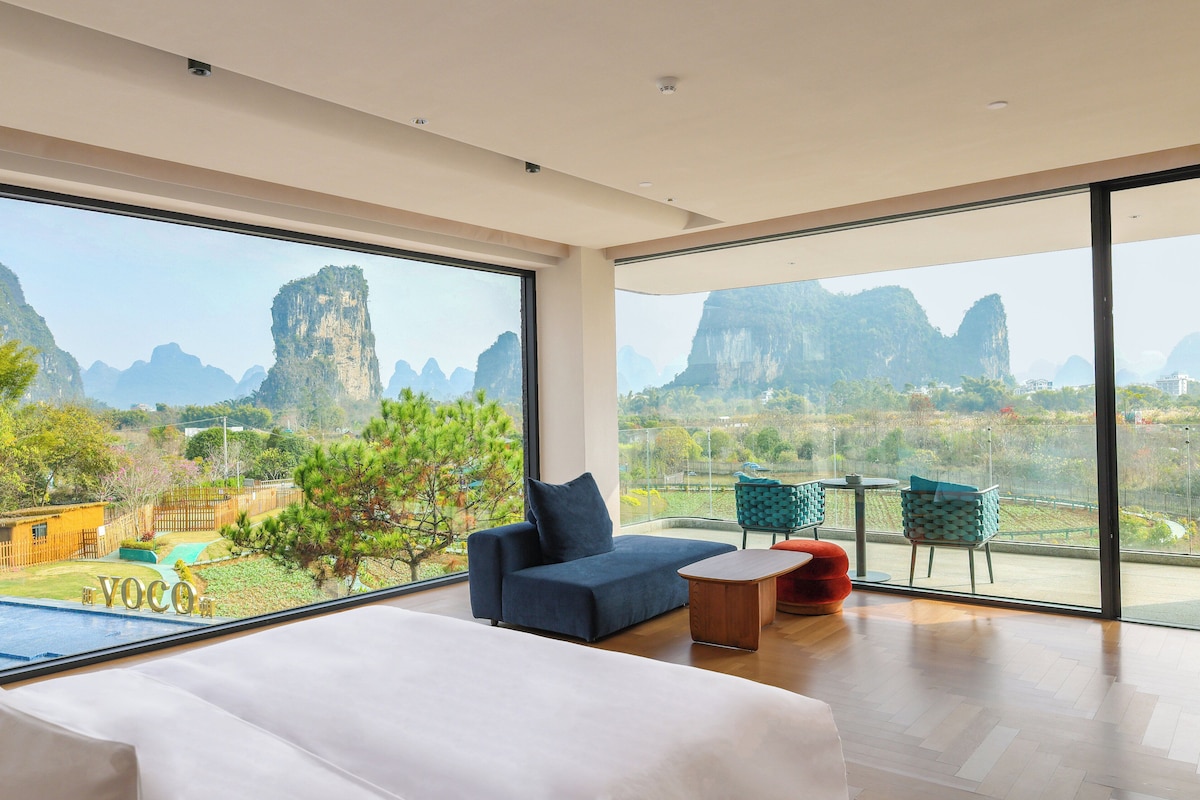 A modern hotel room with a large window offering a view of mountainous landscape.