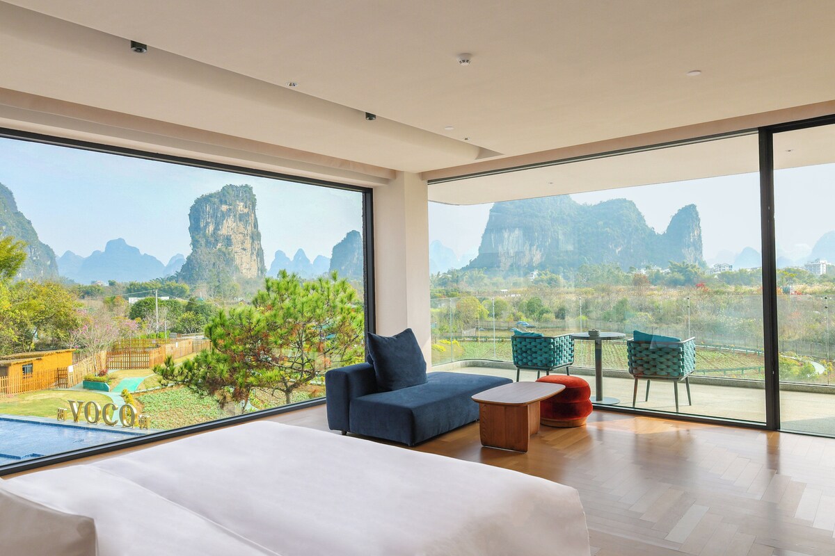 Une chambre d’hôtel moderne dotée d’une grande fenêtre donnant sur un paysage montagneux.