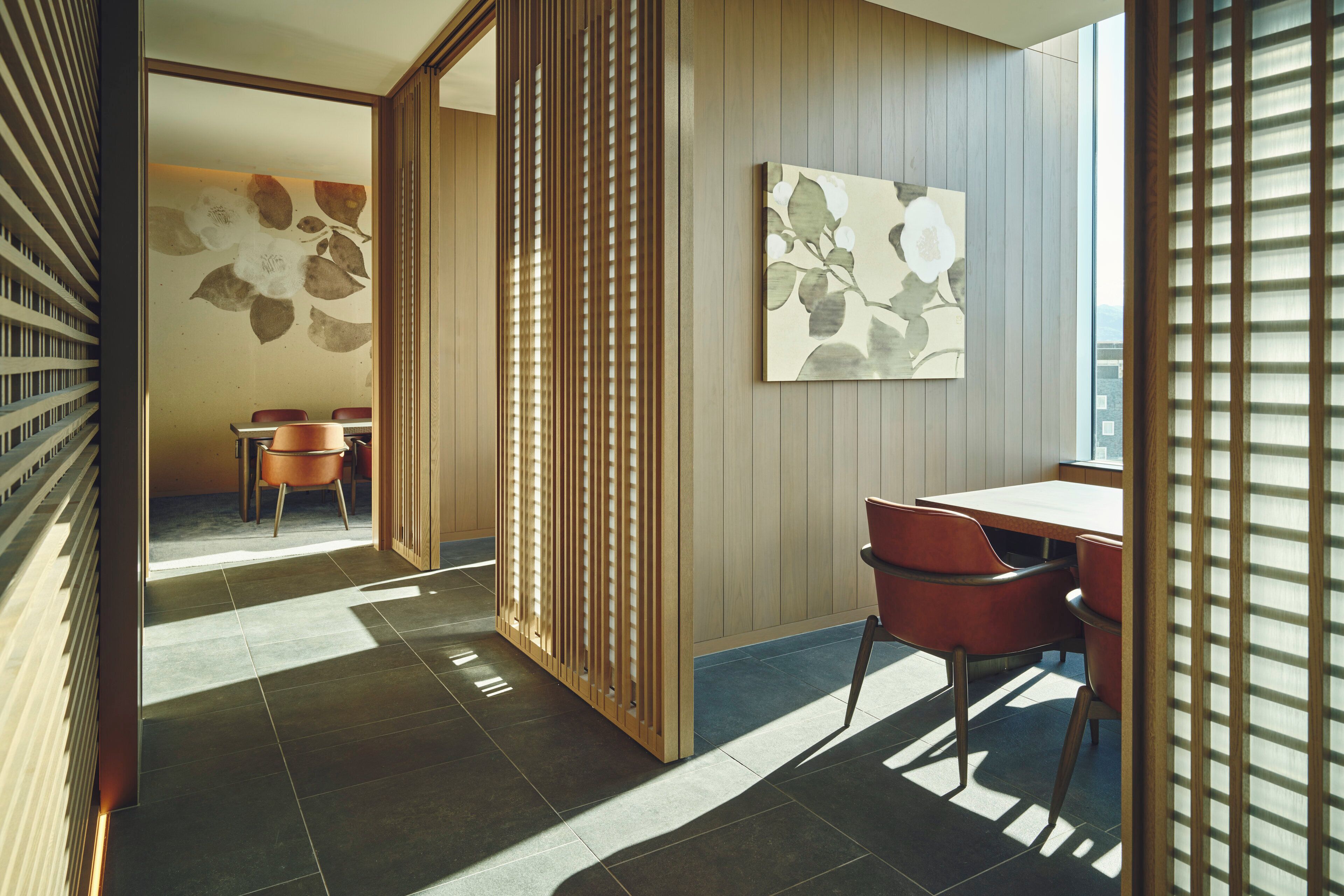 A modern interior with a wooden partition, a dining area with chairs, and a table.