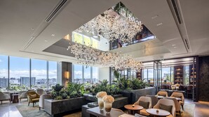 A spacious lobby with a high ceiling, large windows, and a view of the city. There are seating areas, a bar, and a reception desk. - InterContinental Sapporo by IHG (Sapporo)