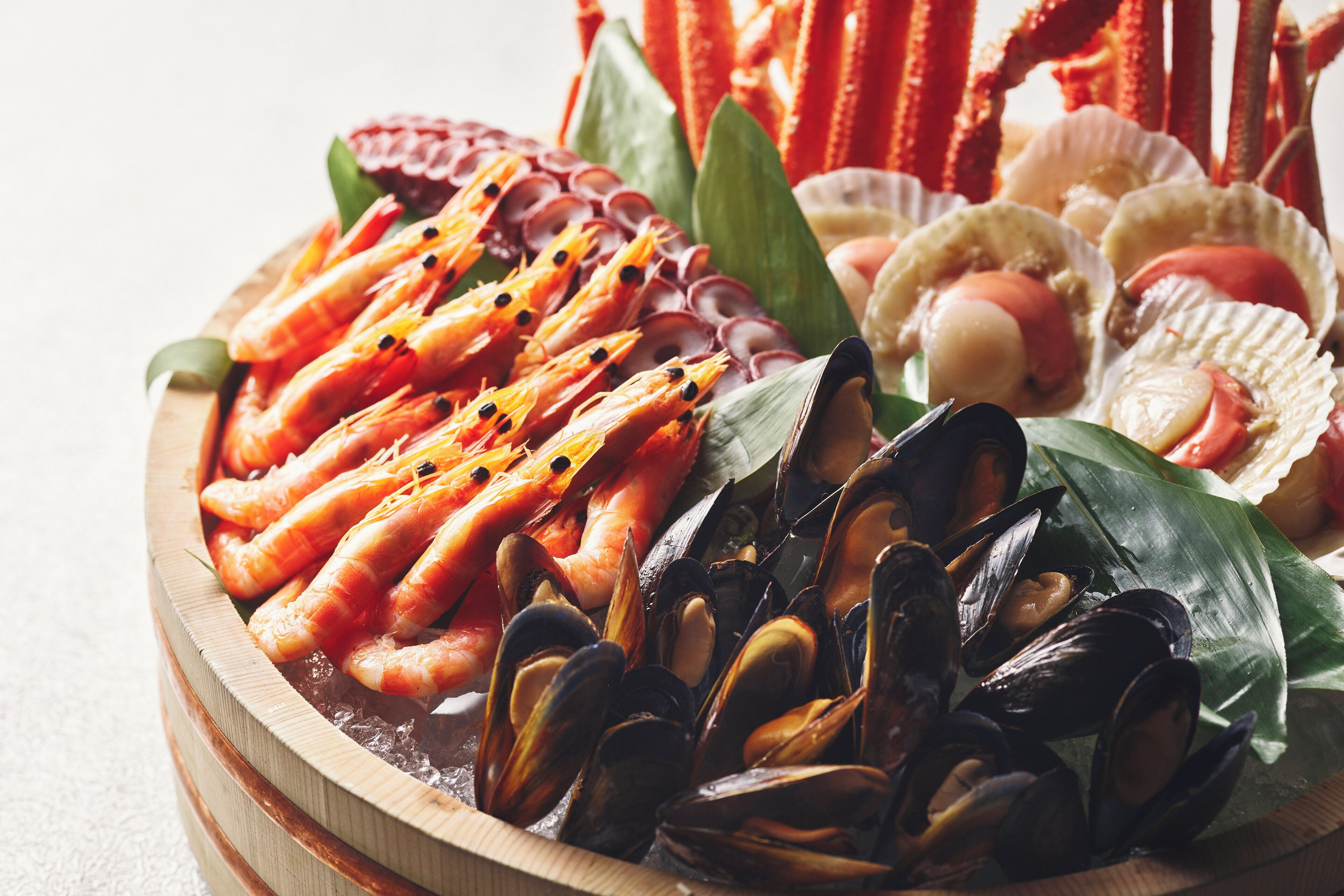 A variety of seafood including shrimp, mussels, and scallops arranged on a wooden platter.