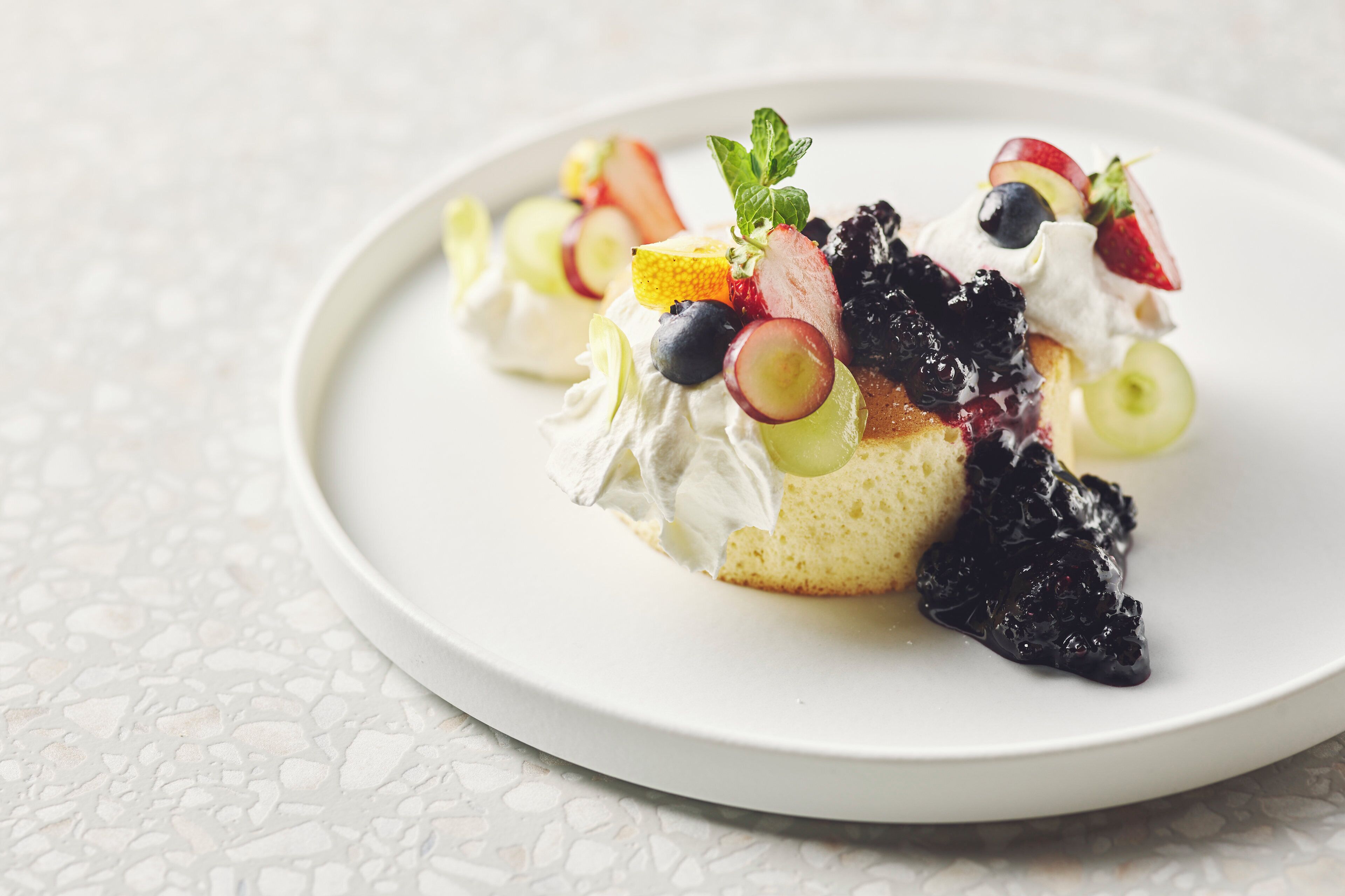 A dessert on a white plate with fruit and cream.
