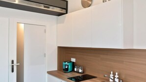 A modern kitchen with white cabinetry, a wooden countertop, a built-in stove, and a stainless steel sink.
