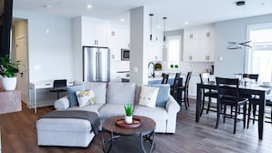 Una cocina moderna con armarios blancos, un refrigerador de acero inoxidable e iluminación colgante.