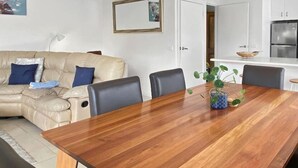 A modern living room with a wooden dining table, leather sofa, and a kitchen area with stainless steel appliances. - Town & Tide, Cowes Central (Cowes)