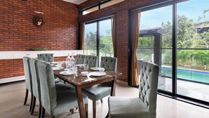 Un espace repas avec un mur en briques, de grandes fenêtres et une vue sur une piscine.