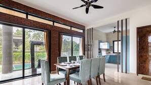 Un espace repas avec un mur en briques, de grandes fenêtres et une vue sur une piscine.
