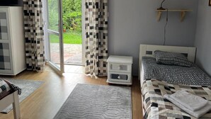 Ein Schlafzimmer mit einem Bett, einem Nachttisch, einem Schreibtisch, einem Stuhl, einem Fenster mit Vorhängen und einem Bild an der Wand.