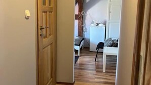 Ein Flur mit Holzboden, einer Tür und einem kleinen Tisch mit Stuhl im Hintergrund.