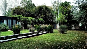 Un jardin avec un étang, un petit abri de jardin et diverses plantes.