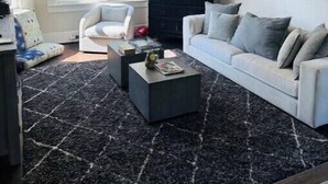 Un salon moderne avec un canapé blanc, une table basse noire et un ventilateur de plafond.