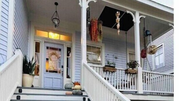 Un escalier menant à un porche doté de balustrades blanches et d’une porte avec une fenêtre.
