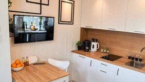 Eine moderne Küche mit weißen Schränken, einer Holzauskleidung und einem eingebauten Backofen, darüber ein flachbildfernseher.