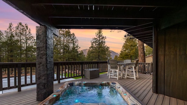 Un jacuzzi en una terraza de madera con vistas a árboles y montañas.