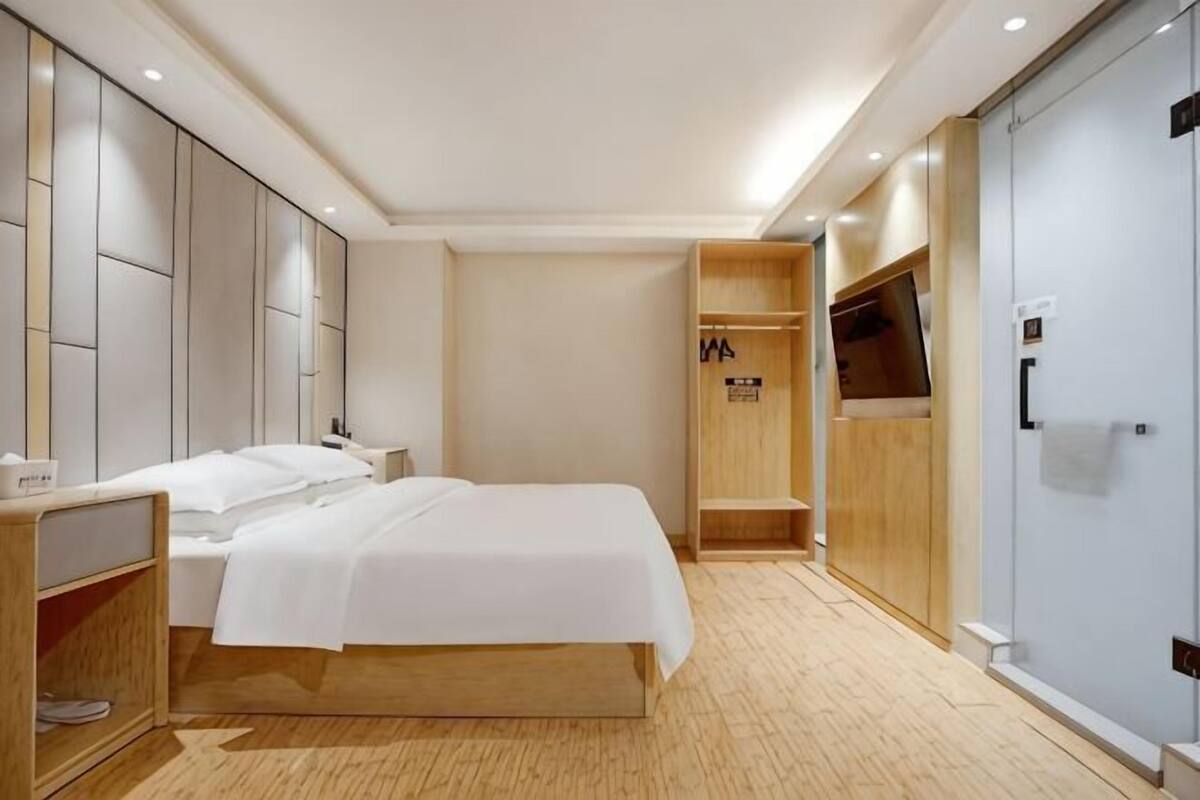 Ein Hotelzimmer mit Bett, Nachttischen, einem Kleiderschrank und einem Spiegel.