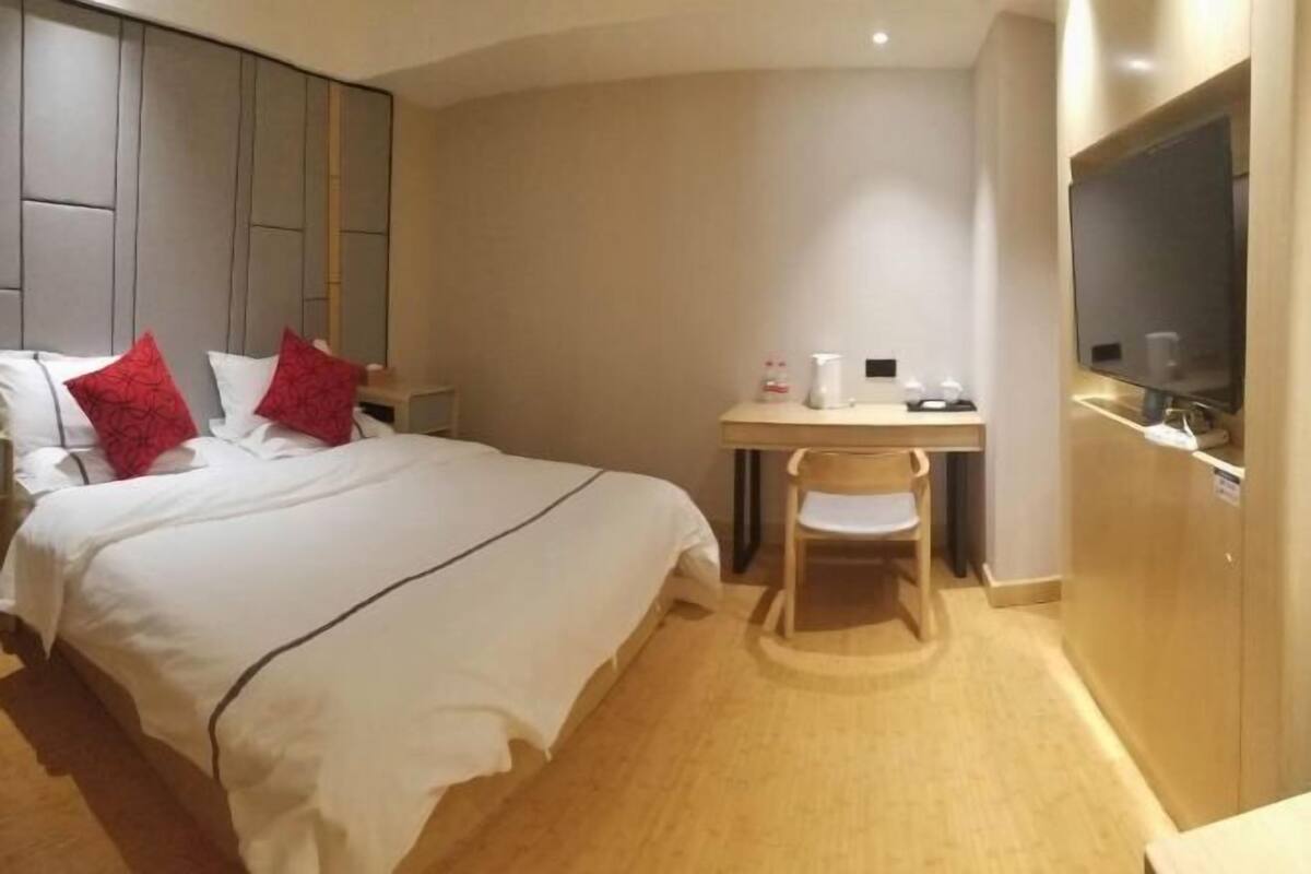 Ein Hotelzimmer mit Bett, Schreibtisch, Stuhl, Fernseher und Kleiderschrank.