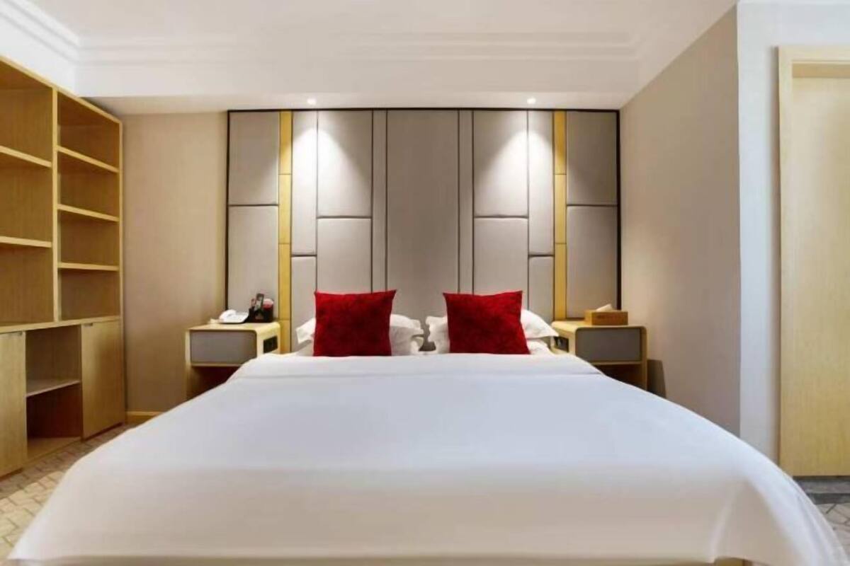 Ein Hotelzimmer mit einem großen Bett, einem Kleiderschrank und einem Nachttisch mit Lampe.