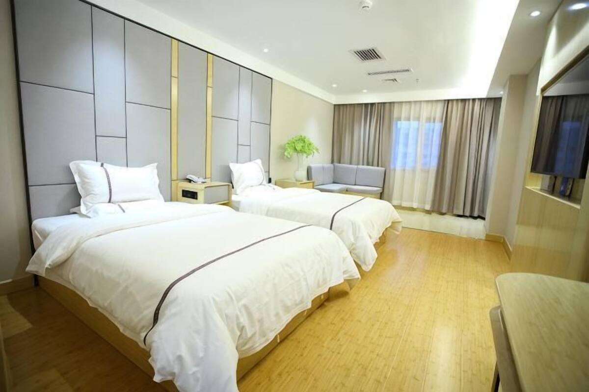 Ein Hotelzimmer mit zwei Betten, einem Schreibtisch, einem Stuhl und einem Fernseher.