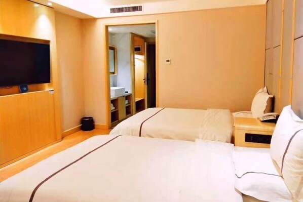 A hotel room with two beds, a TV, a bedside table with a phone, and a bathroom visible through an open door. - Korla New Zheshang Hotel (Bazhou Passenger Transport Terminal) (Korla)