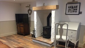 Una sala de estar con chimenea, televisor, aparador de madera y cómoda blanca.