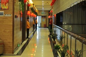 Un corridoio d'hotel con pavimento lucido, rivestimenti in legno sulle pareti e lanterne rosse.