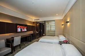 Habitación de hotel con dos camas, un escritorio, un televisor y una zona de estar.