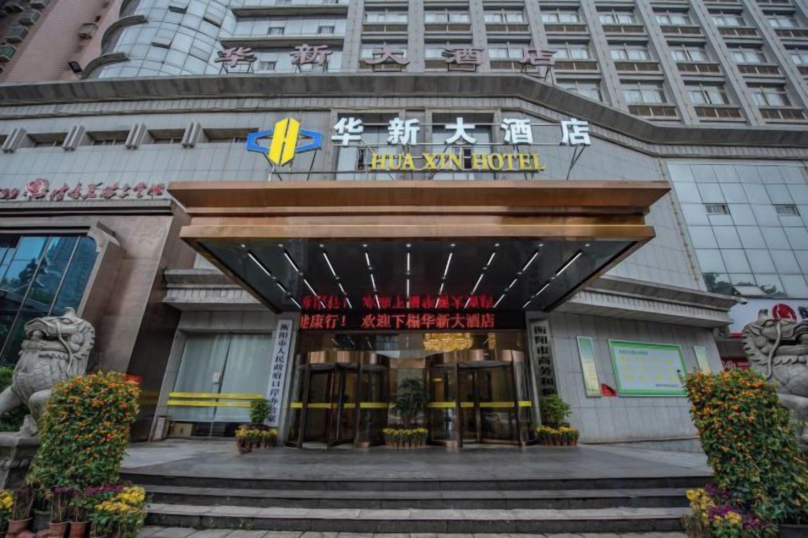 A hotel entrance with a modern facade, a prominent entrance canopy, and decorative plants.