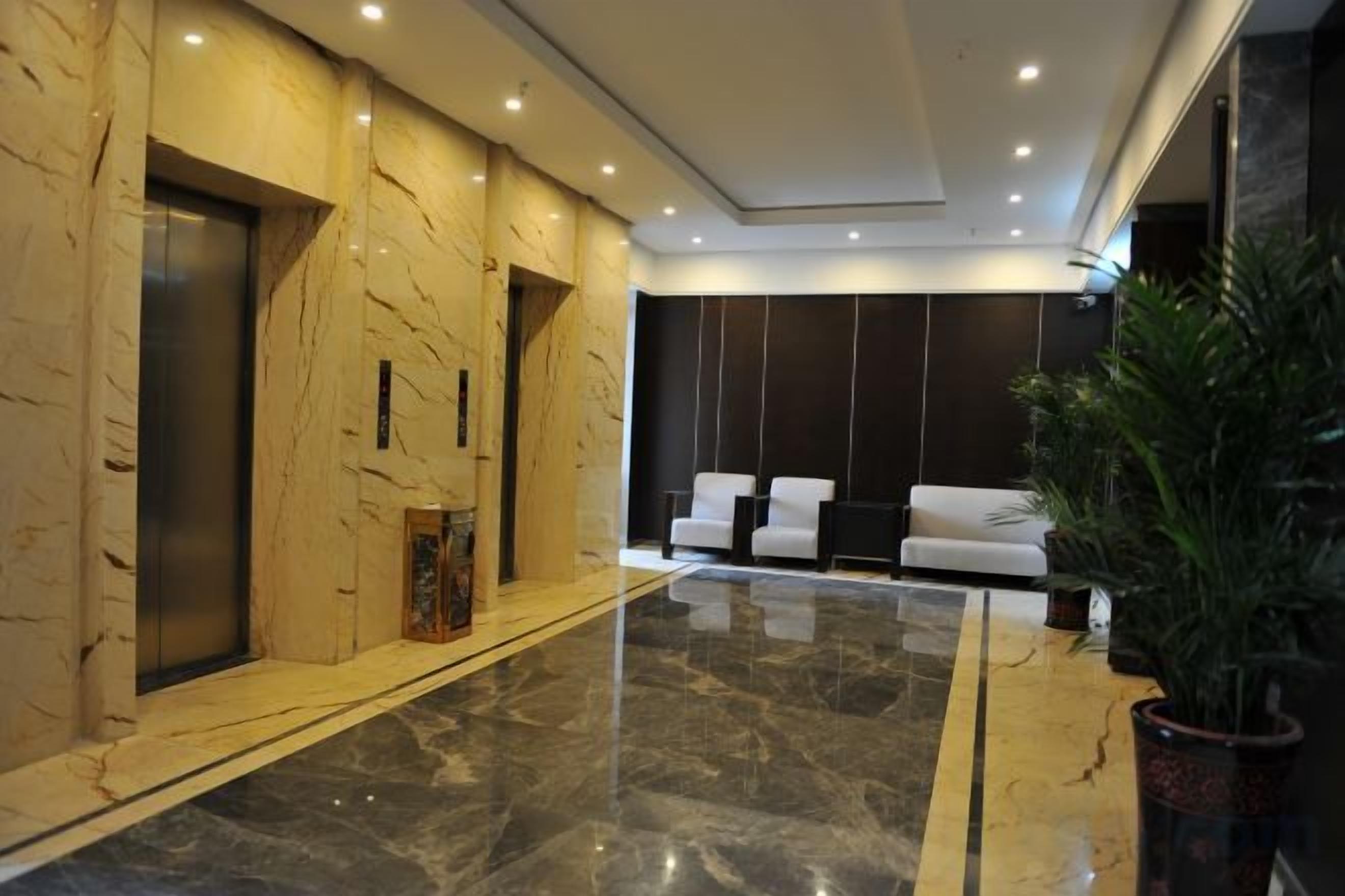 A lobby with marble walls, a reception desk, and a seating area with chairs.