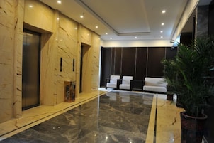 A lobby with marble walls, a reception desk, and a seating area with chairs.