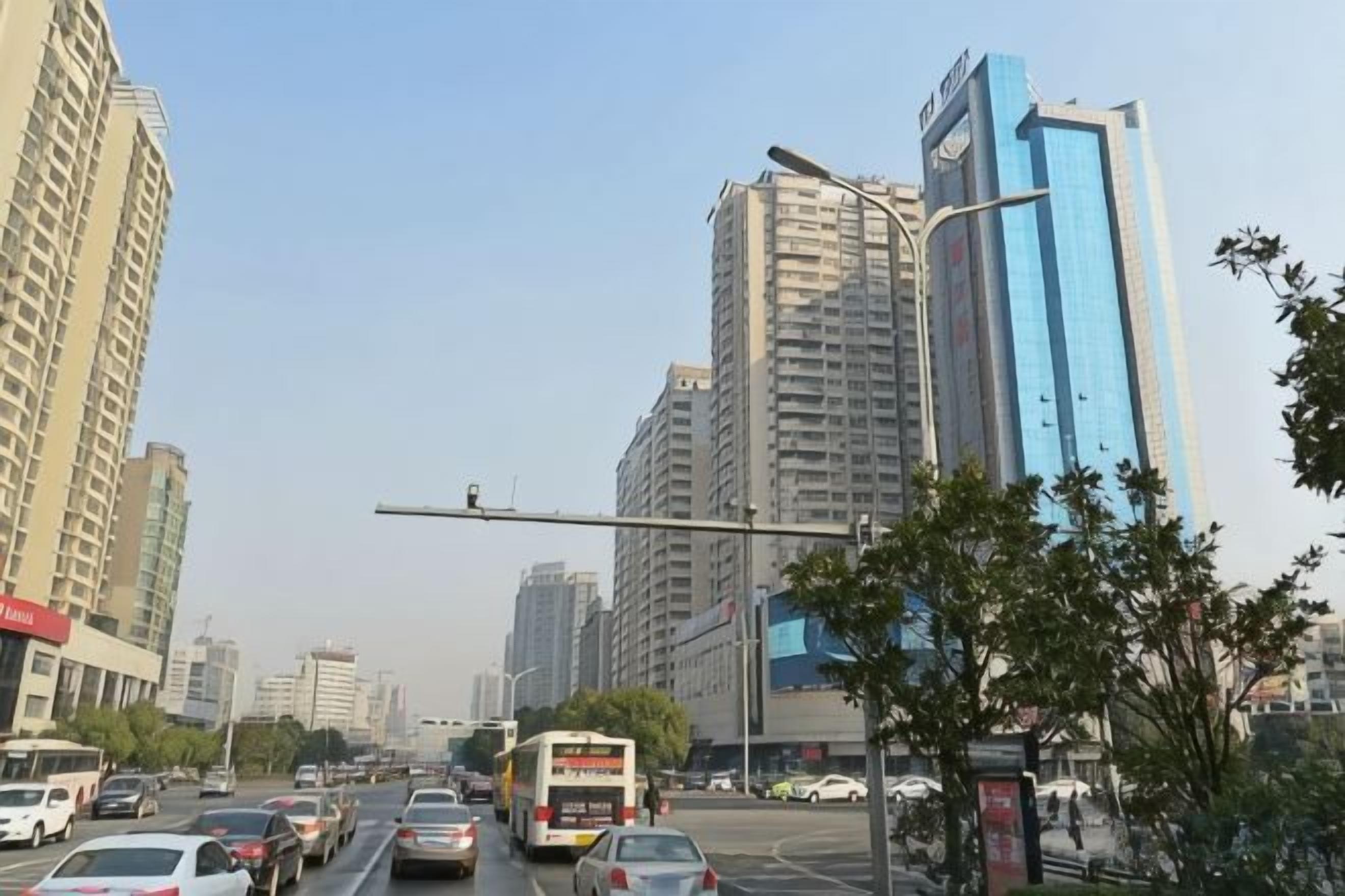 A city street with tall buildings, vehicles, and streetlights.