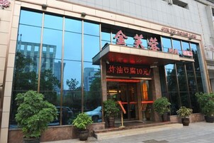 A hotel entrance with a glass facade, potted plants, and a sign indicating a price of 10 yuan.