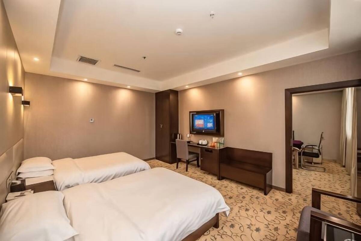 A hotel room with a large bed, a desk, a chair, a television, and a mirror.