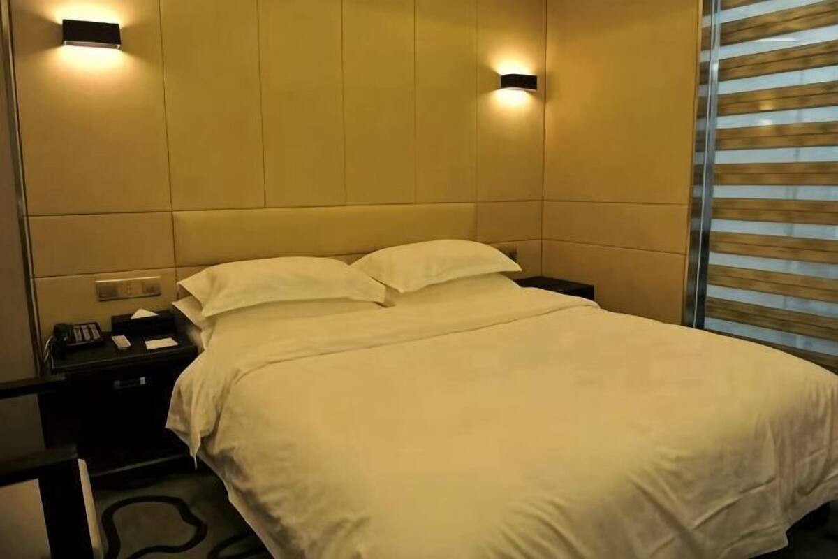 A hotel room with a bed, bedside table, and wall-mounted light fixtures.