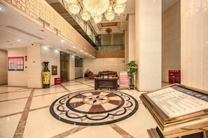 A hotel lobby with a central circular floor design, a reception desk, and a chandelier. - Hua Xin Hotel Hengyang (Hengyang)