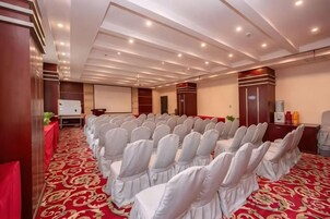 Un salón de conferencias con filas de sillas, un atril y una pantalla de proyección.